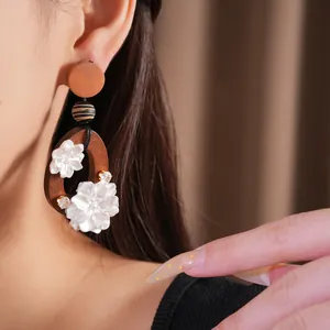 Detalle de pendientes vintage de madera con flores de resina blanca y circón
