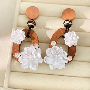 Primer plano de pendientes vintage de madera y flores de resina con circonitas
