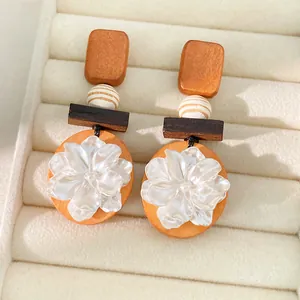 Detalle de pendientes vintage de madera con flor de resina blanca y cuenta rayada.