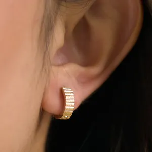 Detalle macro de pendientes de acero dorado con textura acanalada y martilleada