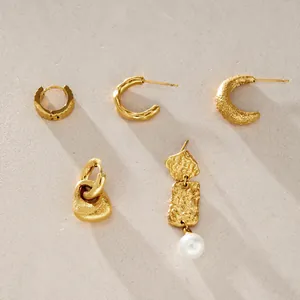 Detalle de pendientes de acero inoxidable dorado con texturas martilladas y perla