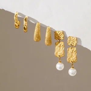 Vista detallada de tres pares de pendientes vintage dorados con textura y perla blanca.