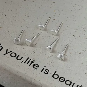 Minimalist silver stud earrings in geometric round and heart shapes with textured finish