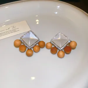 Gros plan de boucles d'oreilles ethniques avec résine blanche, strass et perles en bois.