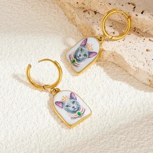 Détail d'une illustration de chat vintage dans des boucles d'oreilles dorées émaillées.