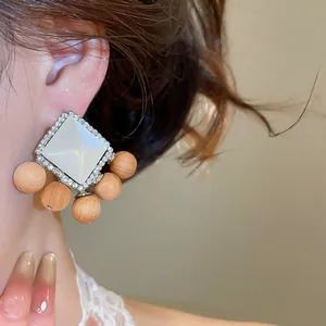 Détail en gros plan de boucles d'oreilles ethniques avec strass, résine et bois.