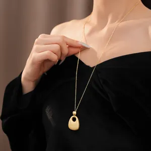 Nahaufnahme einer minimalistischen goldenen Halskette mit rundem Anhänger am Modell.