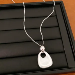 Detailaufnahme einer silbernen Halskette mit organischem Anhänger auf schwarzem Samt.