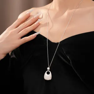 Detailansicht eines minimalistischen silbernen Rundanhängers an einer eleganten langen Kette.