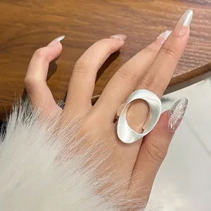 Detail van een matzilveren ovale holle ring gedragen aan de wijsvinger met bont.