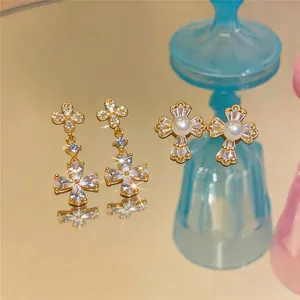 Détail macro de boucles d'oreilles plaquées or 18 carats avec fleurs en zircon et perles