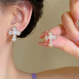 Gros plan sur des boucles d'oreilles croix plaquées or 18 carats avec perle et zircon