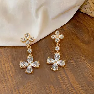 Gros plan de boucles d'oreilles pendantes fleurs en or 18 carats avec oxydes de zirconium