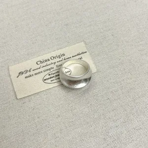 Detailopname van een matzilveren ovale opengewerkte ring op gestructureerde stof