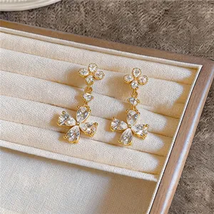 Gros plan exquis de boucles d'oreilles fleurs en zircon plaqué or 18 carats dans un coffret