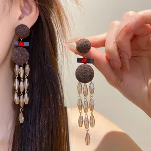 Primer plano de pendientes étnicos vintage con borlas, cuentas de madera y cristales.