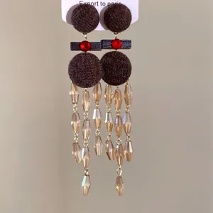 Primer plano de pendientes étnicos con borlas de tela marrón y cuentas de color ámbar
