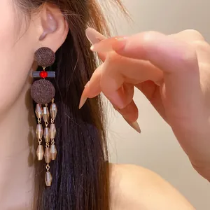 Primer plano de pendientes étnicos vintage con borlas marrones y una piedra roja