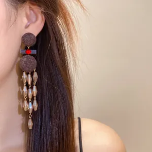 Primer plano de pendientes étnicos con borlas, bolas de fieltro marrón y cristales.