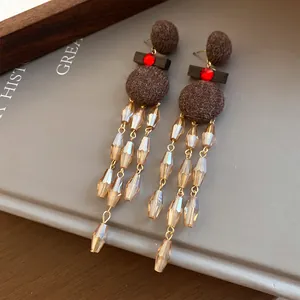 Vista detallada de pendientes étnicos retro con borlas de madera y cuentas de champán.