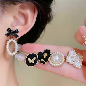 Détail de boucles d'oreilles en perles vintage avec motifs nœud, papillon et fleur.