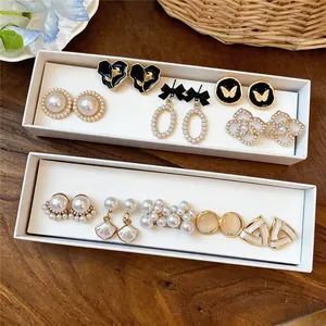 Détails de boucles d'oreilles vintage à perles et dorées dans des boîtes d'exposition.
