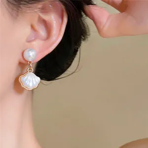 Gros plan de boucles d'oreilles élégantes en perles et coquillages portées par un mannequin