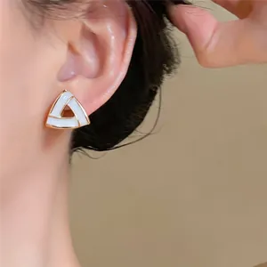 Vue détaillée d'une élégante boucle d'oreille triangulaire blanche et dorée