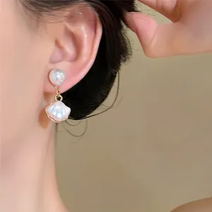 Gros plan d'élégantes boucles d'oreilles perles style français avec pendentif de coquillage