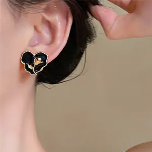 Détail d'une boucle d'oreille cœur en émail noir de style français avec rose dorée