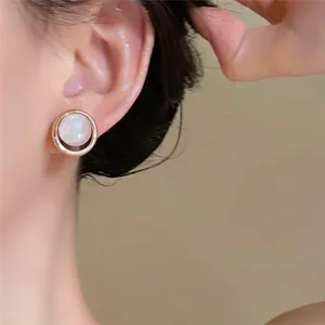 Gros plan de magnifiques boucles d'oreilles perles rondes vintage français avec bord doré.