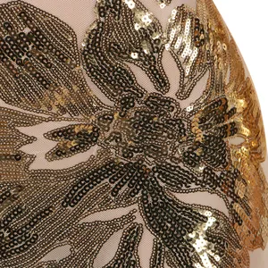 Dettaglio ravvicinato di ricamo floreale in paillettes dorate su tessuto mesh nude