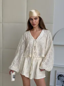Elegante completo a due pezzi in pizzo bianco con cardigan con lacci e shorts abbinati.