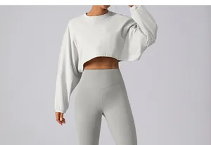 Close-up detail of a women's light grey cropped sweatshirt and high waist yoga pants