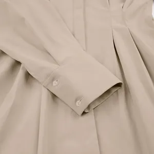 Detailopname van de manchet van een kaki hemdjurk met knopen en geplooide taille.