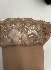 Hautfarbene, glänzende Nylon-Oberschenkelstrümpfe mit Pfauenspitzenbesatz und Silikonband.
