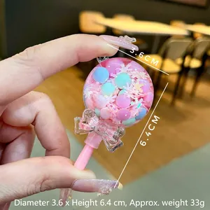 Close-up of pink lollipop liquid sand charm with colorful beans and snowflakes.