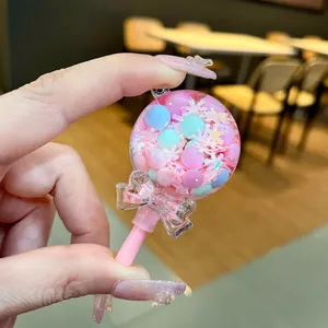 Handheld close-up of a pink lollipop shaker keychain with colorful beads and glitter.
