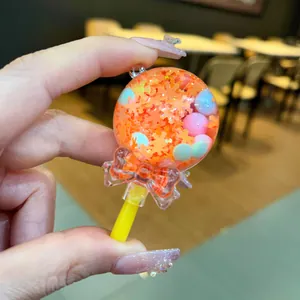 Close-up view of a liquid oil-filled lollipop shaker charm with orange maple leaf glitters