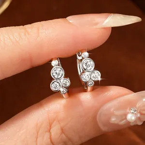 Κοντινό πλάνο με ασημένια σκουλαρίκια moissanite με ακανόνιστο σχέδιο στρογγυλής πέτρας