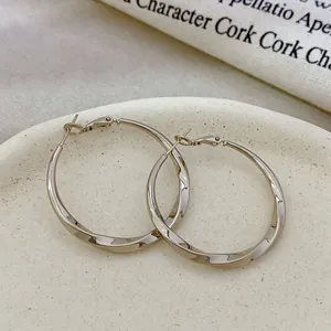Close-up of elegant copper gold plated twisted hoop earrings with a shiny finish