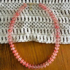 Detailed macro close-up of a pink natural stone abacus bead necklace with gold clasp.
