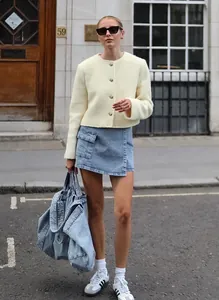 Model trägt eine schicke, cremefarbene Kurzjacke aus Wolle auf einer Stadtstraße