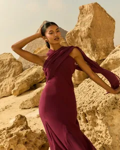 Détail d'une robe en mousseline bordeaux avec un long ruban fluide sur fond de désert ancien.