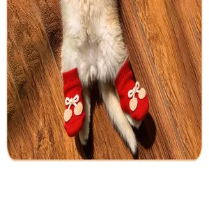 Macro view of cute red knit pet socks with cream heart-shaped bear ear patches