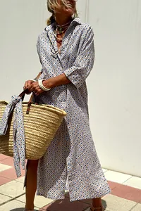 Woman wearing a patterned maxi shirt dress styled with a woven straw bag outdoors