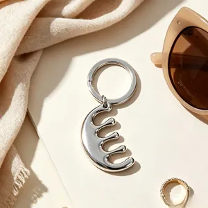 Macro detail of a minimalist silver stainless steel comb-shaped keychain on beige board