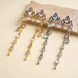 Detalle de pendientes de borla geométrica con gotas brillantes en oro y plata