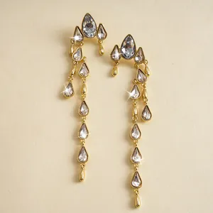 Primer plano de elegantes pendientes de borla dorados con brillantes strass.