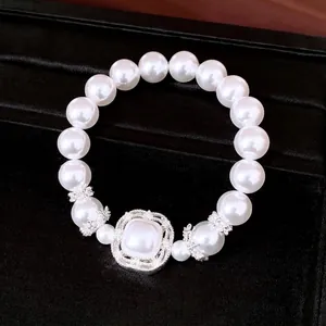 Elegante pulsera elástica de perlas con dije de circón sobre terciopelo negro